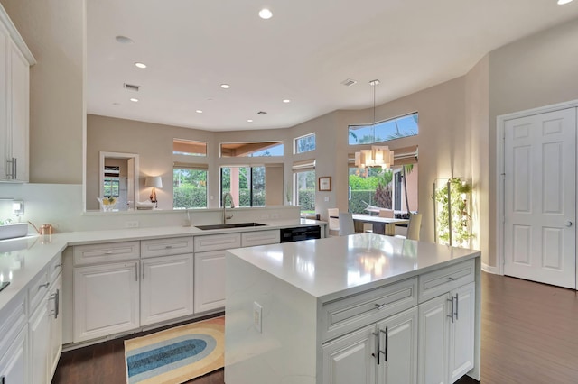 kitchen with a kitchen island, dark hardwood / wood-style flooring, a notable chandelier, sink, and white cabinets