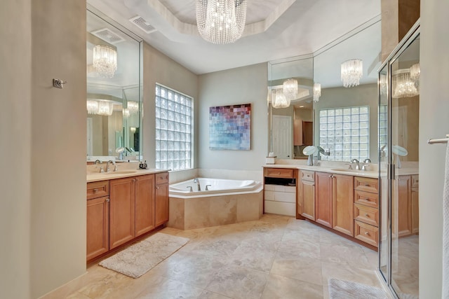 bathroom featuring a tray ceiling, vanity, separate shower and tub, and an inviting chandelier