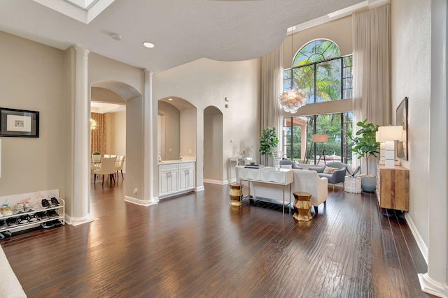 16106 Rosecroft Ter, Delray Beach, FL 33446 - living room featuring arched walkways, a towering ceiling, dark wood-style floors, and baseboards