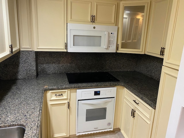 kitchen with cream cabinetry, white appliances, and decorative backsplash