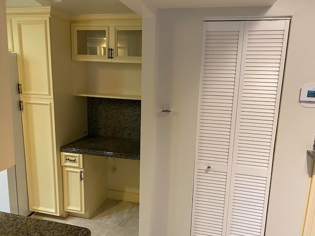 interior space with built in desk, light tile patterned floors, cream cabinetry, and decorative backsplash