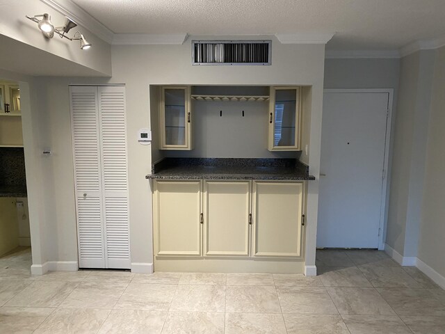 kitchen with ornamental molding, light tile patterned flooring, and a textured ceiling