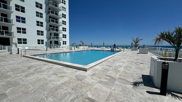 view of swimming pool with a patio area and a water view