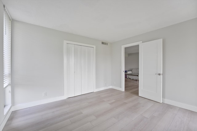 unfurnished bedroom with a closet and light hardwood / wood-style floors