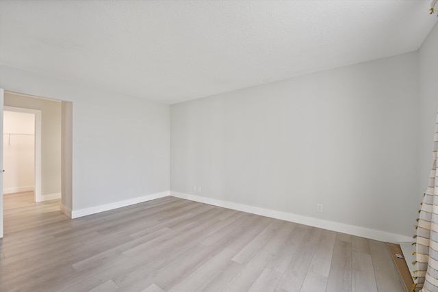 spare room featuring a textured ceiling and light hardwood / wood-style flooring