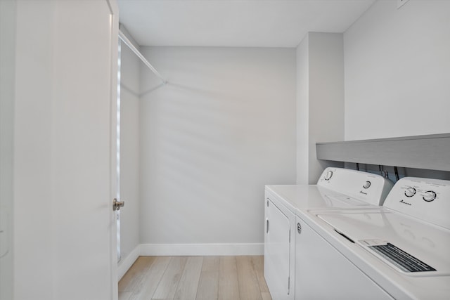 laundry area featuring washing machine and dryer and light hardwood / wood-style flooring