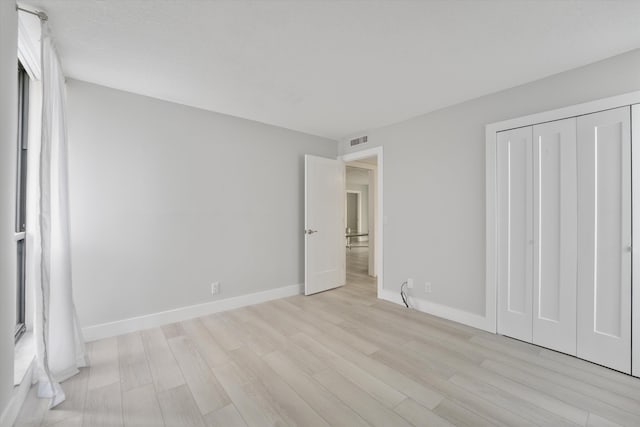 unfurnished bedroom with a closet and light hardwood / wood-style flooring