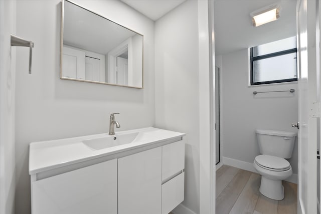 bathroom with walk in shower, vanity, toilet, and hardwood / wood-style floors