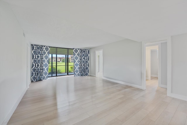 spare room featuring light hardwood / wood-style flooring and floor to ceiling windows