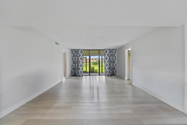 spare room featuring a textured ceiling and light hardwood / wood-style flooring