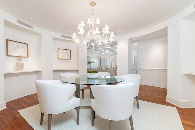 dining room featuring crown molding, hardwood / wood-style floors, and a notable chandelier