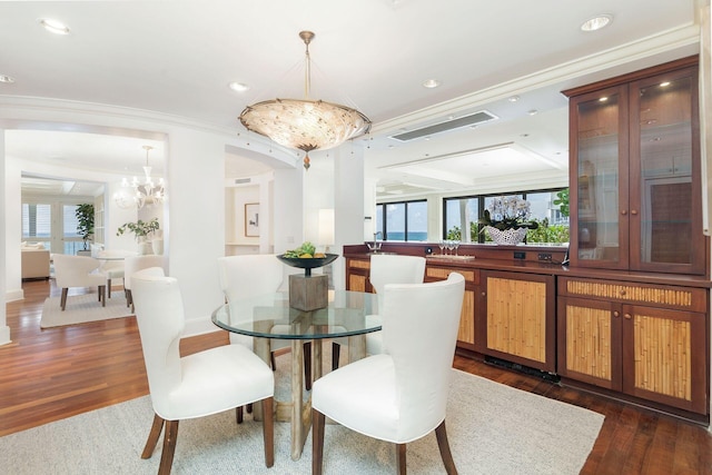 dining space featuring ornamental molding, a notable chandelier, dark wood-type flooring, and a wealth of natural light