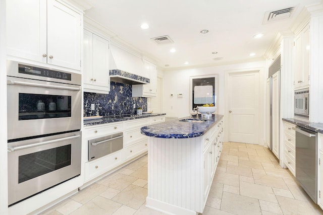 kitchen featuring appliances with stainless steel finishes, a center island, decorative backsplash, and white cabinetry