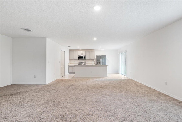 unfurnished living room featuring sink, light carpet, and a textured ceiling