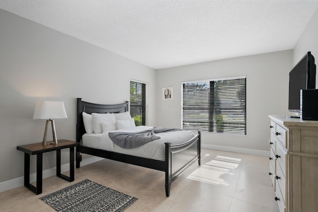 bedroom with a textured ceiling and multiple windows