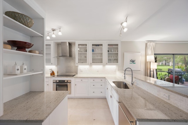 kitchen featuring stainless steel appliances, sink, light stone countertops, and wall chimney exhaust hood