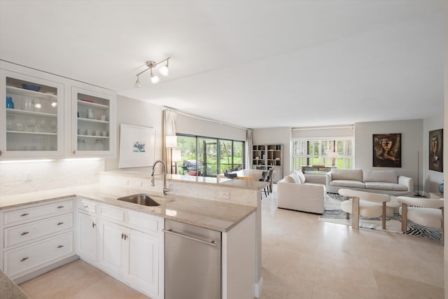 kitchen with white cabinets, kitchen peninsula, sink, and light stone countertops