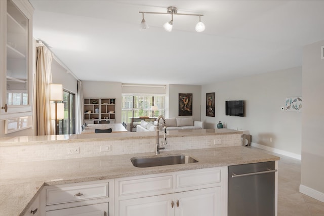 kitchen with light tile patterned floors, light stone counters, white cabinetry, and sink