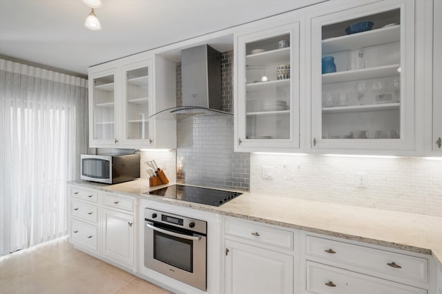 kitchen with light stone countertops, wall chimney exhaust hood, backsplash, appliances with stainless steel finishes, and white cabinets