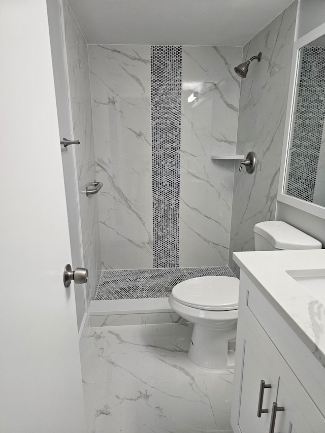 bathroom featuring vanity, toilet, and a tile shower