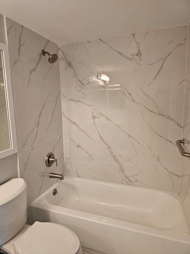 bathroom featuring tiled shower / bath combo and toilet