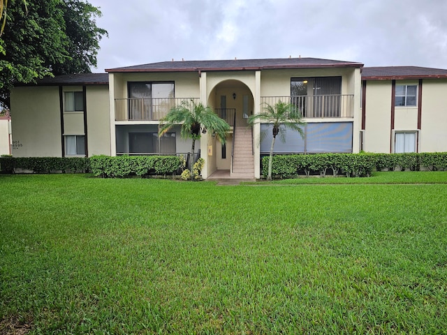 view of front facade with a front lawn and a balcony