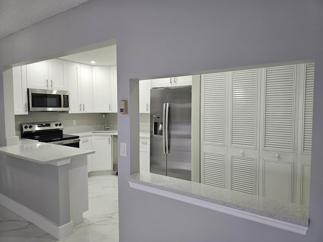 kitchen with stainless steel appliances, light stone counters, sink, kitchen peninsula, and white cabinets