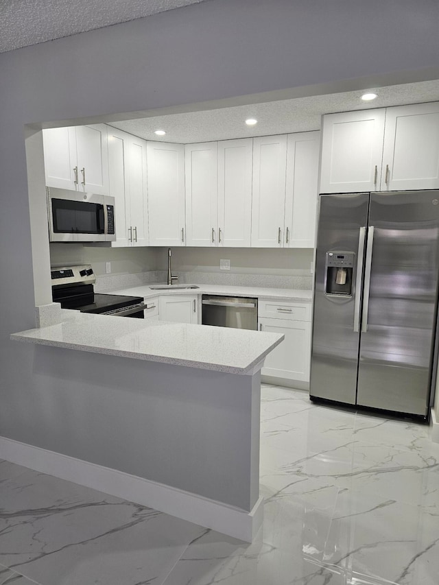 kitchen featuring appliances with stainless steel finishes, kitchen peninsula, white cabinetry, and sink