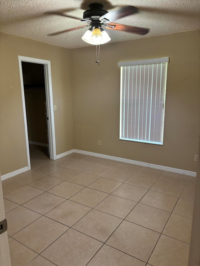 tiled empty room with a textured ceiling and ceiling fan