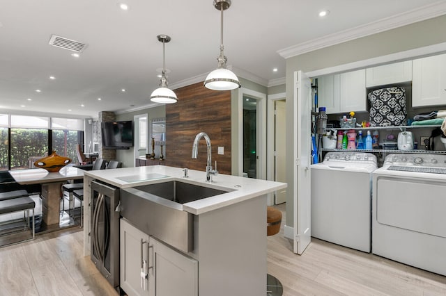 kitchen with light wood-type flooring, independent washer and dryer, sink, and white cabinets