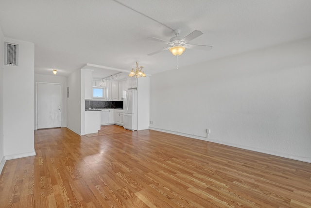 unfurnished living room featuring light wood-type flooring and ceiling fan with notable chandelier