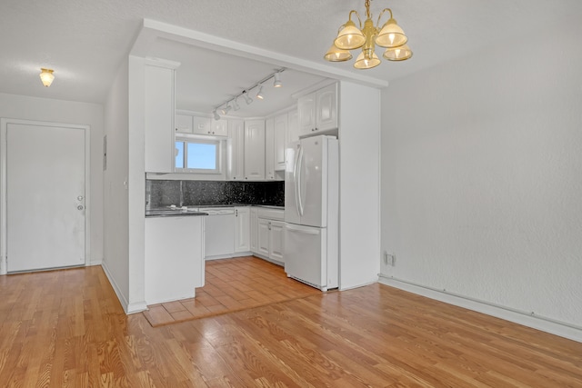 kitchen featuring white refrigerator, an inviting chandelier, light hardwood / wood-style floors, and white cabinets