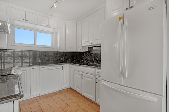 kitchen featuring white appliances, range hood, sink, white cabinetry, and dark stone countertops