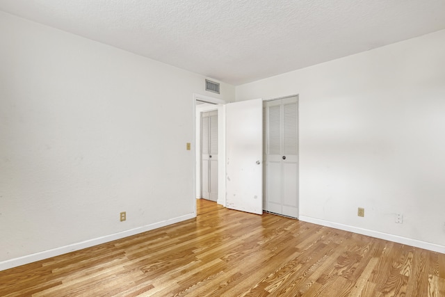 unfurnished room with a textured ceiling and light hardwood / wood-style flooring