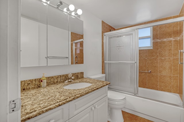 full bathroom featuring combined bath / shower with glass door, vanity, toilet, and tile patterned flooring