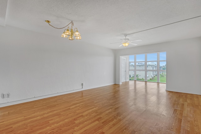 spare room with ceiling fan with notable chandelier, a textured ceiling, and light hardwood / wood-style flooring