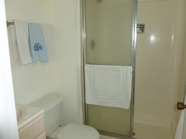 bathroom featuring toilet, vanity, and walk in shower