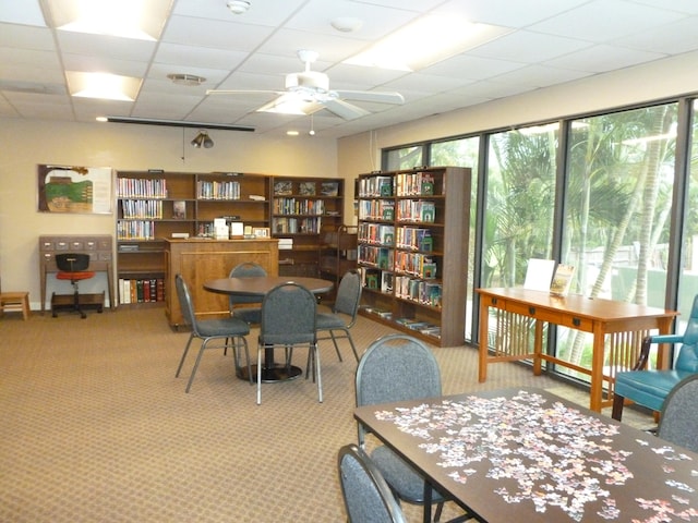 carpeted office with ceiling fan and a drop ceiling