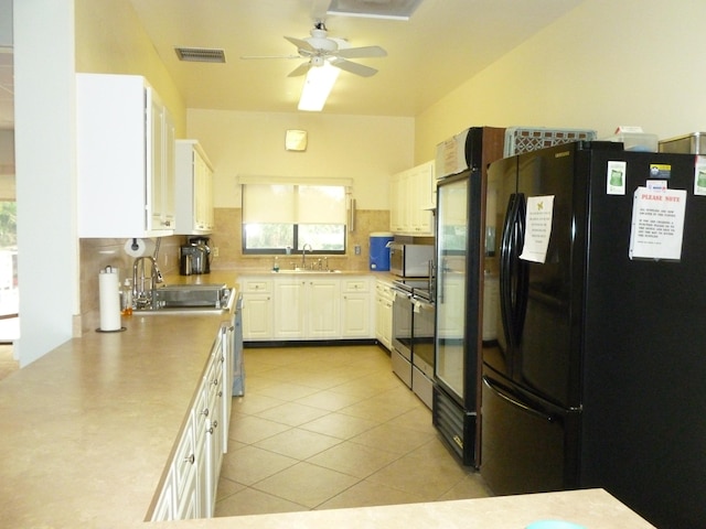 kitchen with white cabinetry, sink, ceiling fan, black fridge, and decorative backsplash