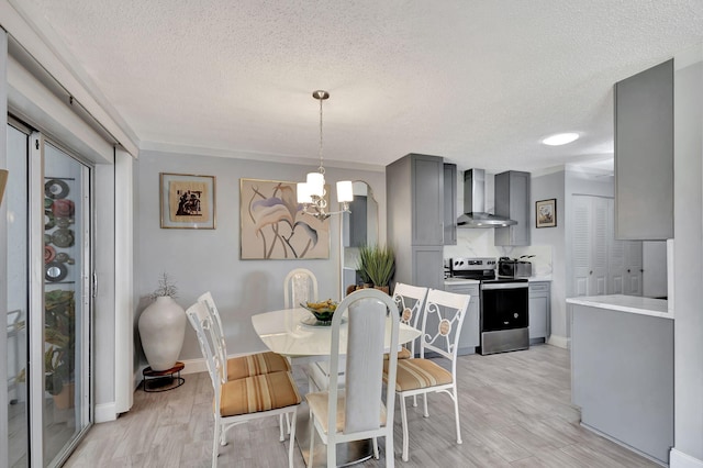 dining area with a textured ceiling, a notable chandelier, and light hardwood / wood-style flooring