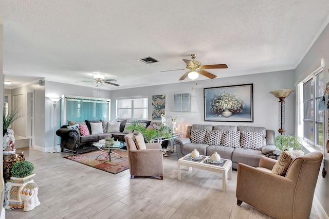 living room featuring a textured ceiling, a healthy amount of sunlight, ceiling fan, and light wood-type flooring