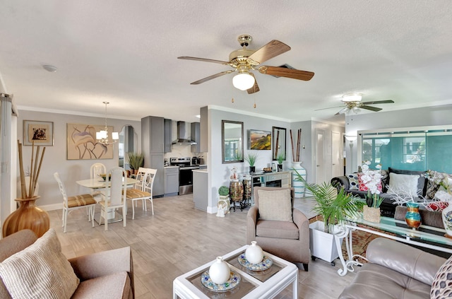 living room featuring ceiling fan with notable chandelier, light wood-type flooring, crown molding, and a textured ceiling