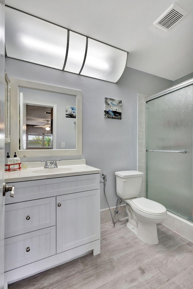 bathroom featuring vanity, toilet, wood-type flooring, and walk in shower