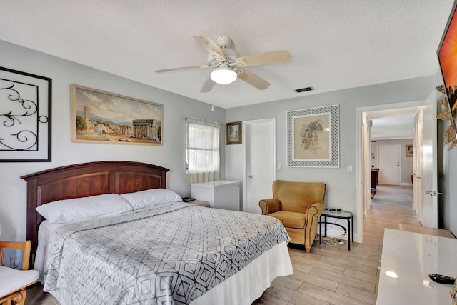 bedroom with light wood-type flooring, a textured ceiling, and ceiling fan