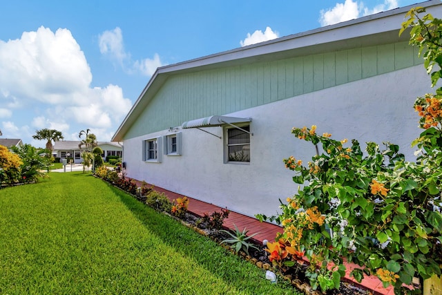 view of side of property with a yard and stucco siding
