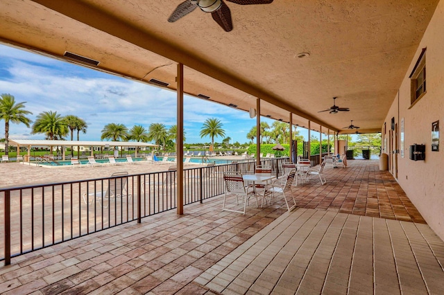 view of patio with a ceiling fan, a community pool, outdoor dining area, and fence