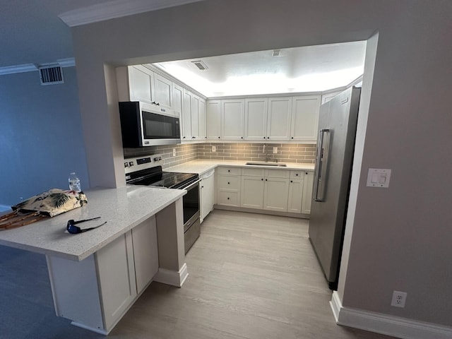 kitchen with backsplash, appliances with stainless steel finishes, sink, white cabinetry, and light wood-type flooring