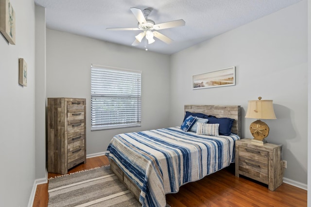 bedroom featuring ceiling fan, dark hardwood / wood-style flooring, and a textured ceiling