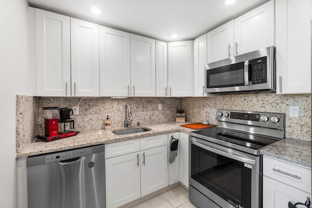 kitchen with sink, white cabinetry, backsplash, appliances with stainless steel finishes, and light stone countertops