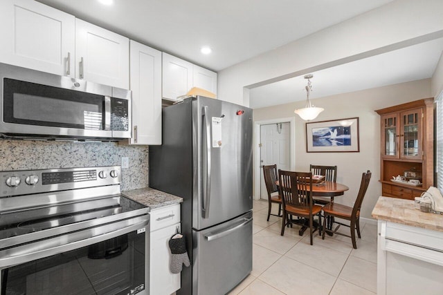 kitchen with white cabinets, light tile patterned floors, decorative light fixtures, stainless steel appliances, and decorative backsplash